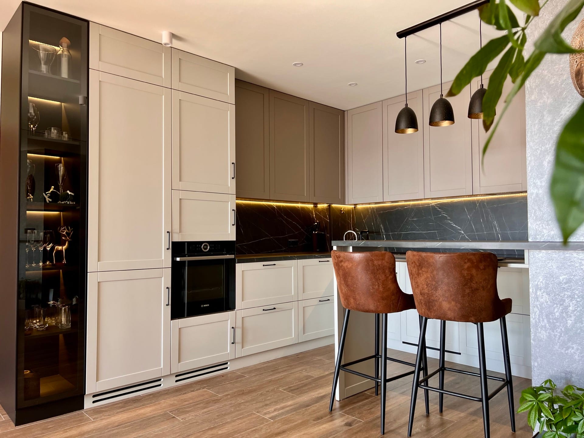 Modern kitchen in an apartment in Bečići, Montenegro: light cabinet fronts, a dark marble-look backsplash, and bar stools.