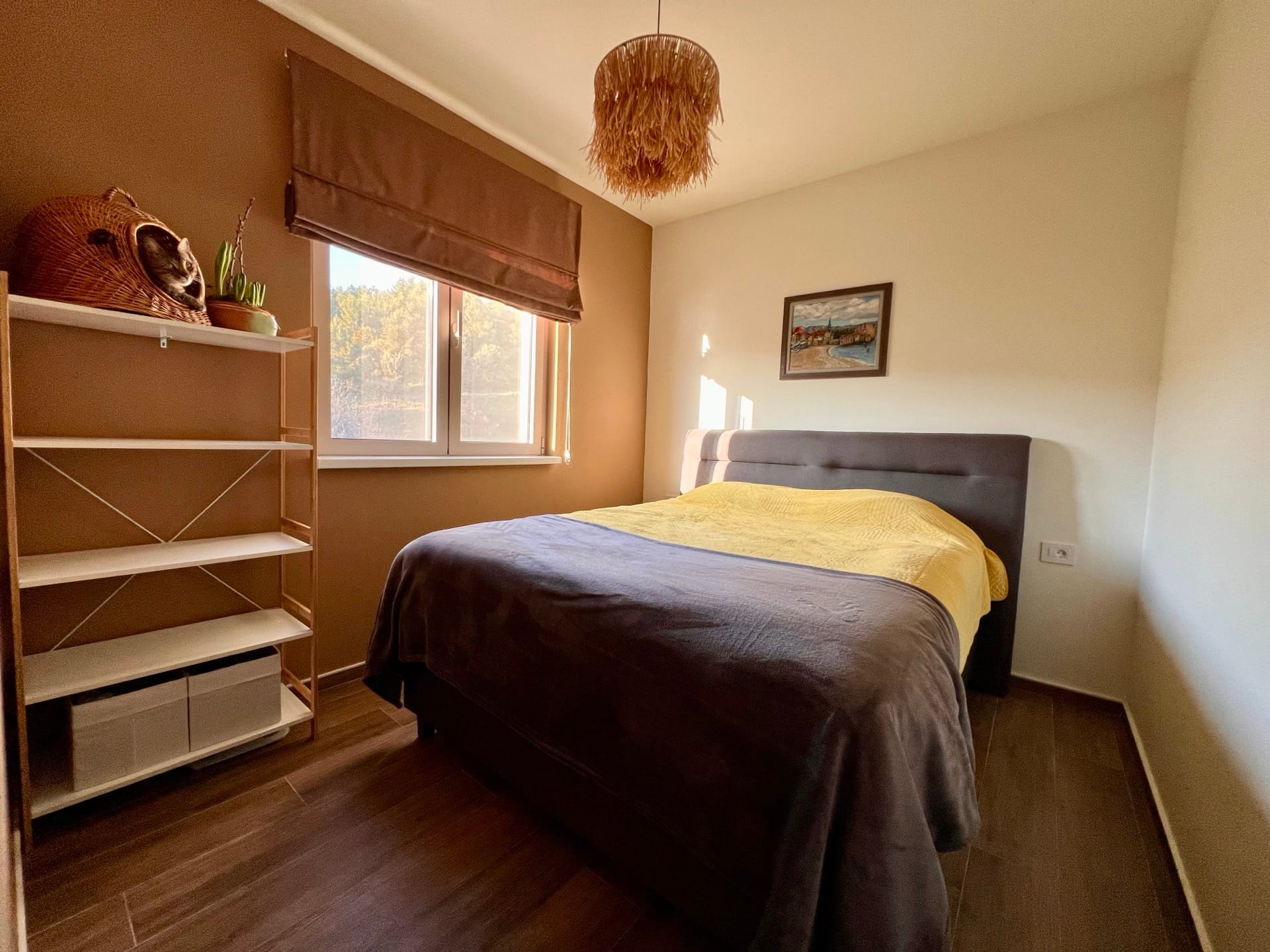 Cozy bedroom with a double bed in an apartment in Bečići, Montenegro: stylish interior, shelving unit, and a view from the window.