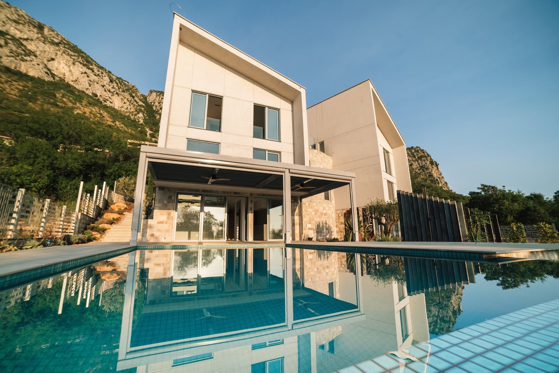 Modern villa with a pool and terrace in Blizikuće, Montenegro: front view and mountain scenery.