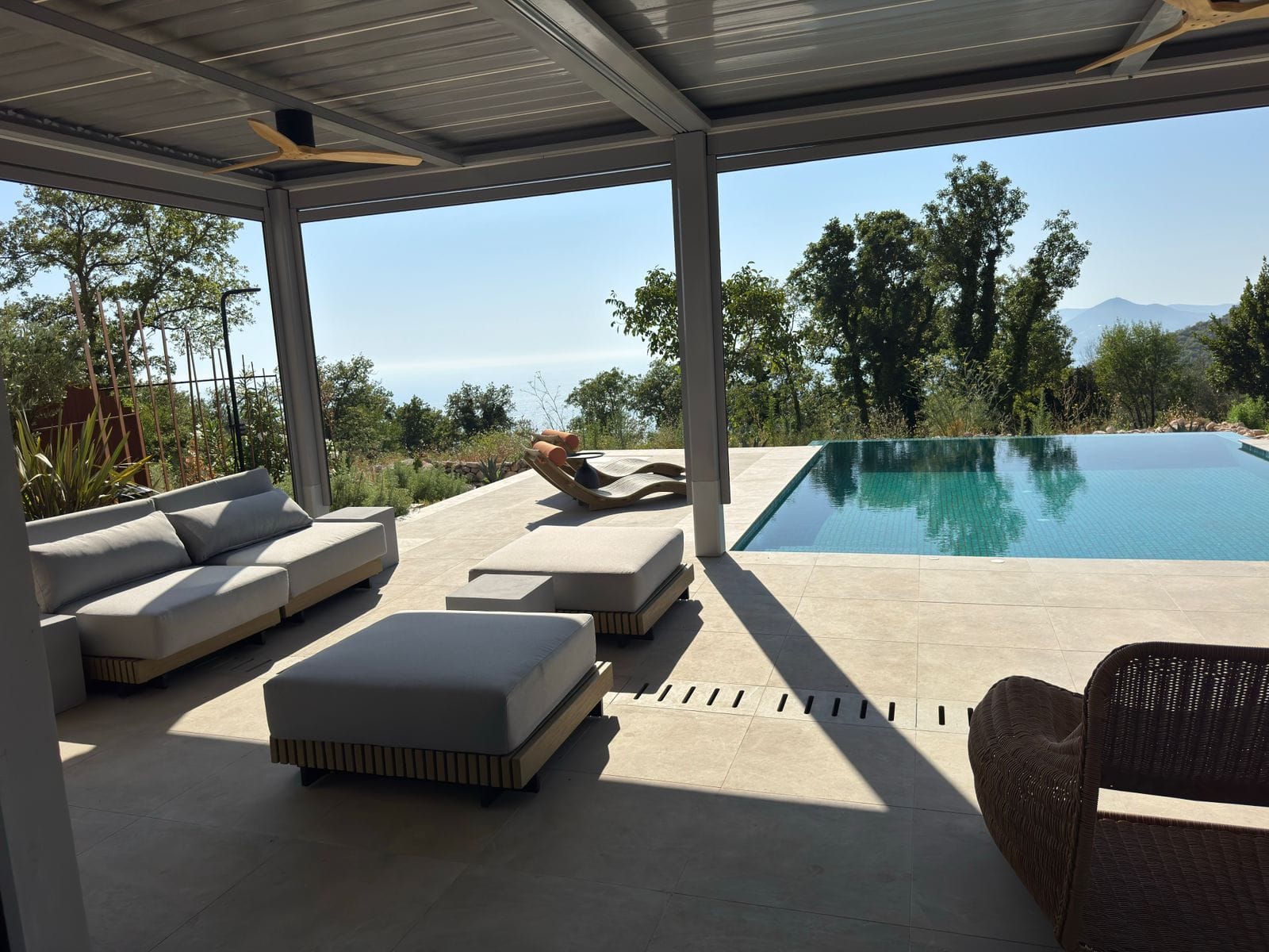 Villa terrace in Blizikuće, Montenegro: lounge area with soft seating, infinity pool, and panoramic sea view.