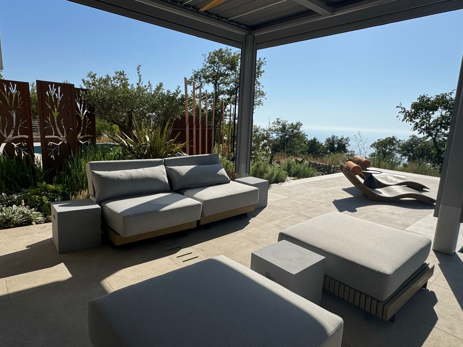 Villa terrace in Blizikuće, Montenegro: modern furniture, sun loungers, and panoramic sea and garden views.