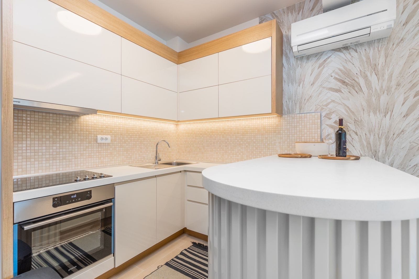Modern kitchen with white fronts and a breakfast bar in a penthouse, Pržno, Montenegro. Built-in appliances and lighting.