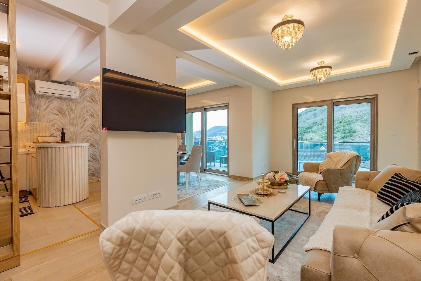 Modern living room with kitchen in a penthouse, Pržno, Montenegro: stylish furniture, panoramic windows, and mountain views.