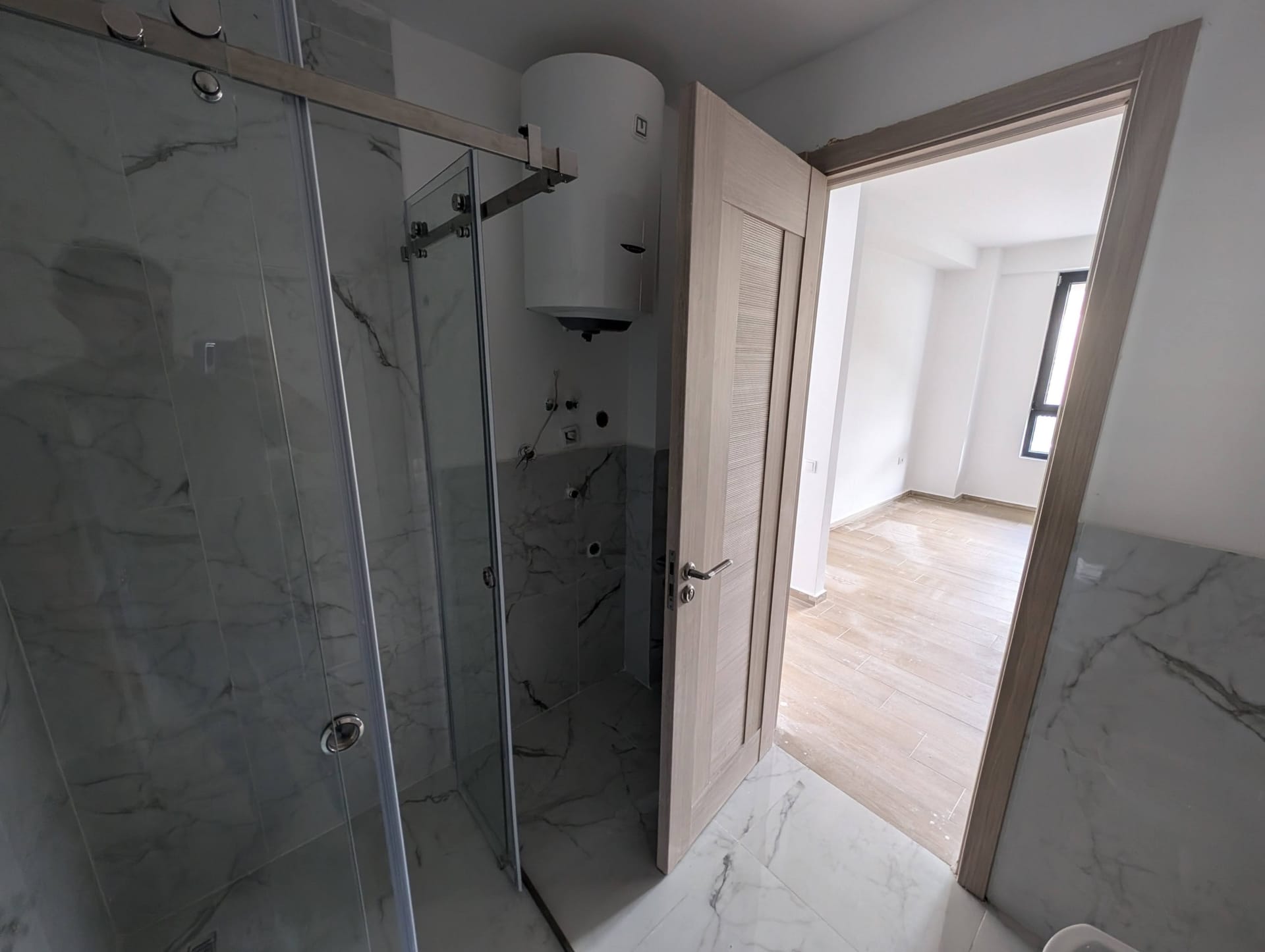 Bathroom with a shower cabin and boiler in a new apartment in Rafailovici, Montenegro, finished with porcelain stoneware.