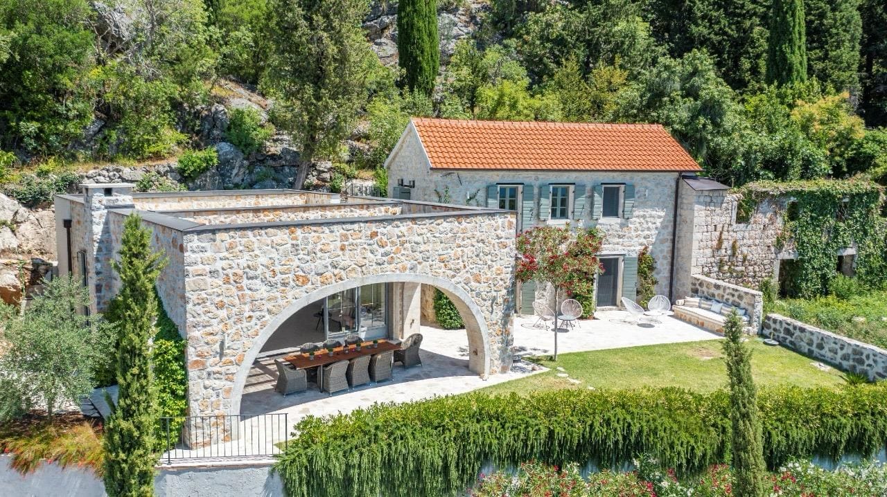 Stone villa in Herceg Novi, Montenegro: terrace with dining area, landscaped garden, and mountain view.