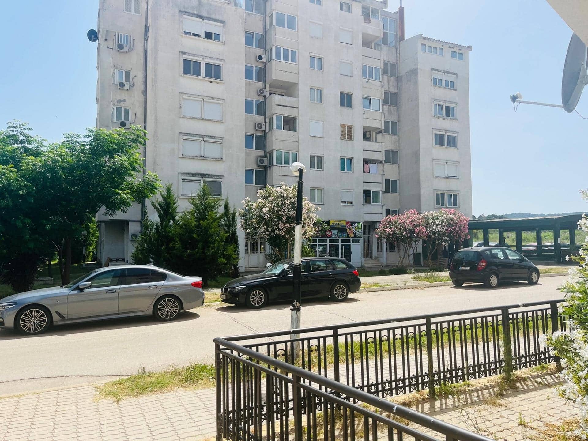 Multi-story residential building in Sutomore, Montenegro: view of the building facade, the grounds, and parking at the entrance.