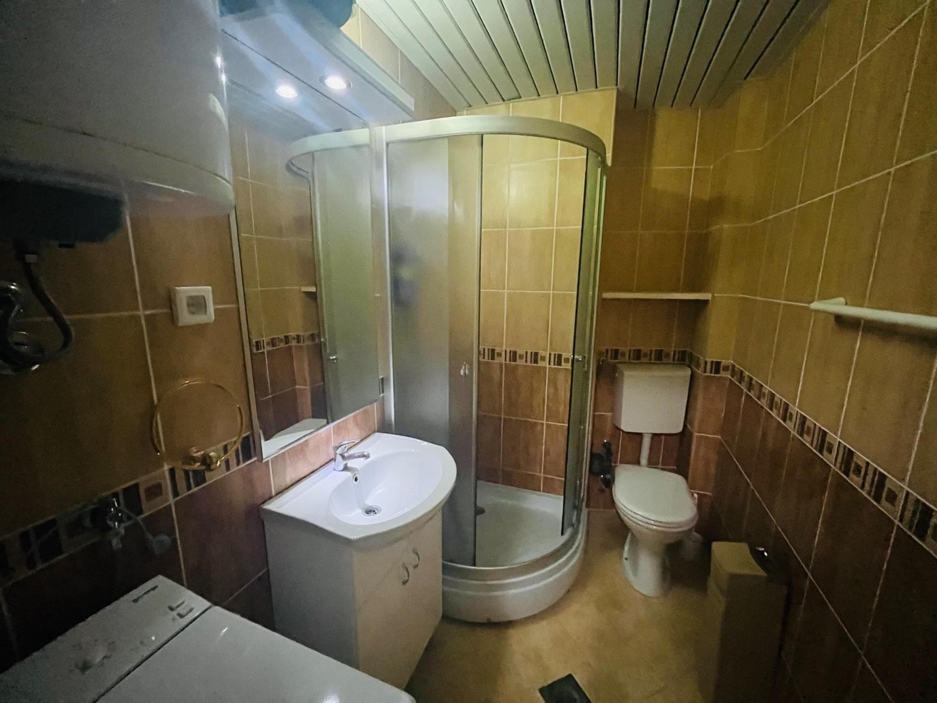 Bathroom in an apartment in Sutomore, Montenegro: shower cabin, vanity with sink, mirror, and tiled finish.