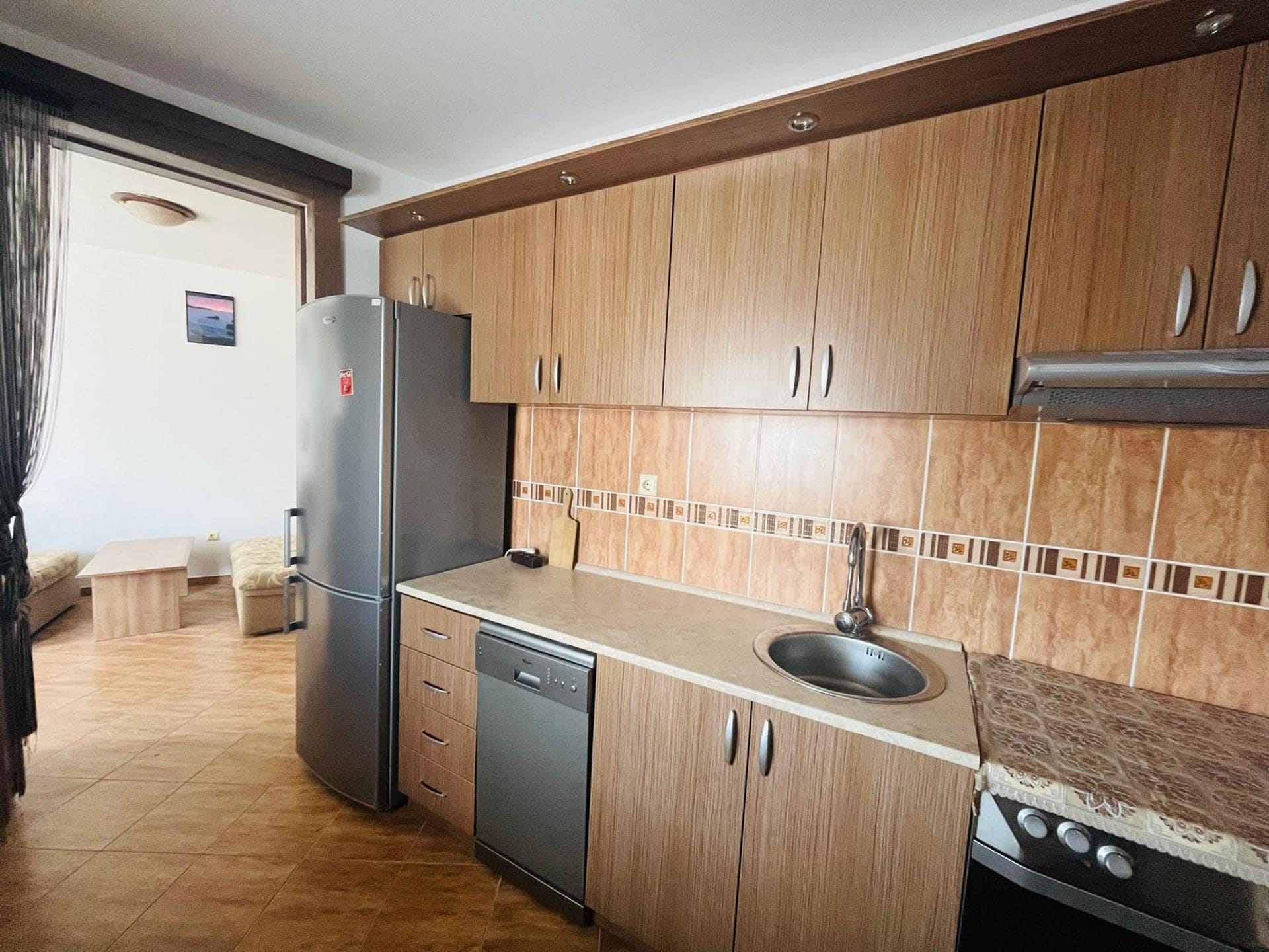 Kitchen with wooden cabinets, a dishwasher, and a refrigerator in an apartment in Sutomore, Montenegro.