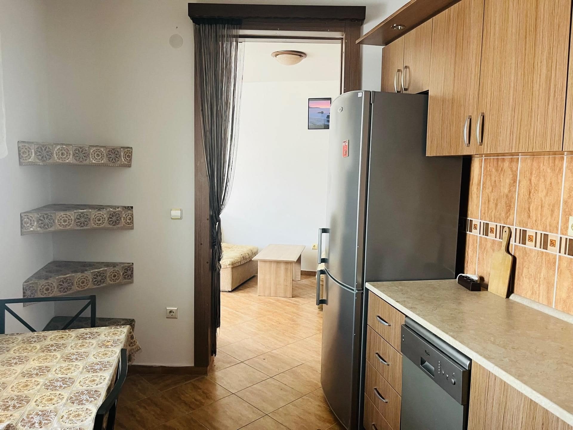 Kitchen with wooden cabinets and appliances in an apartment in Sutomore, Montenegro: view of the dining area and living room.