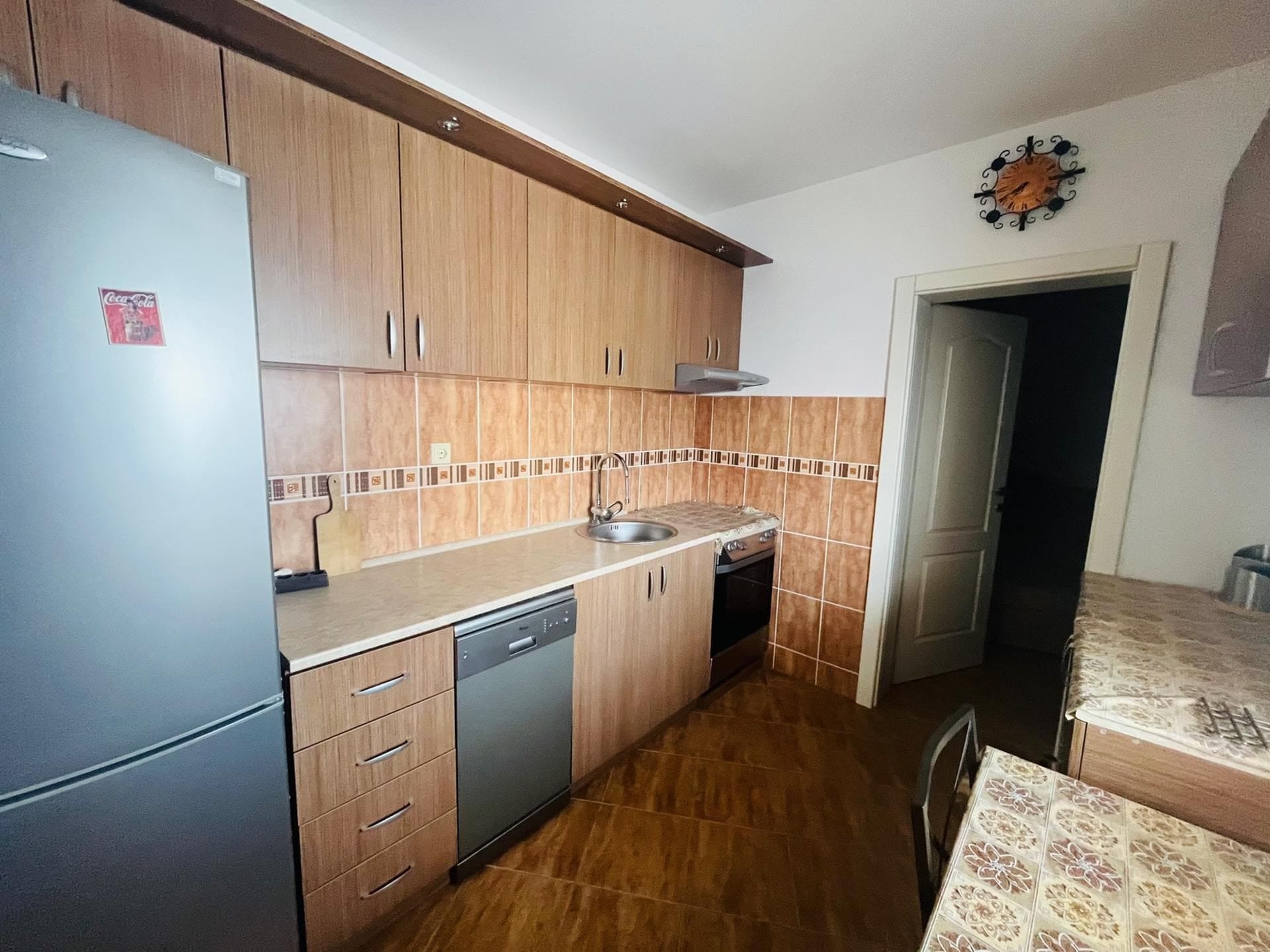 Kitchen in an apartment in Sutomore, Montenegro: wooden cabinets, built-in appliances, tile flooring, and a dining area.
