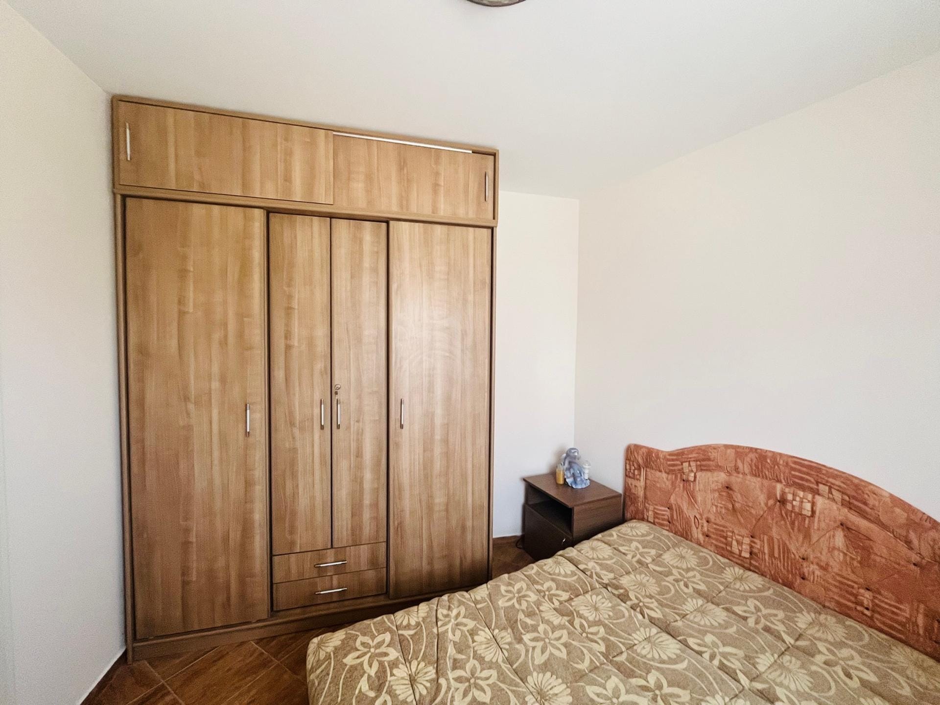 Bedroom in an apartment in Sutomore, Montenegro: a double bed with a patterned bedspread and a large wooden wardrobe.