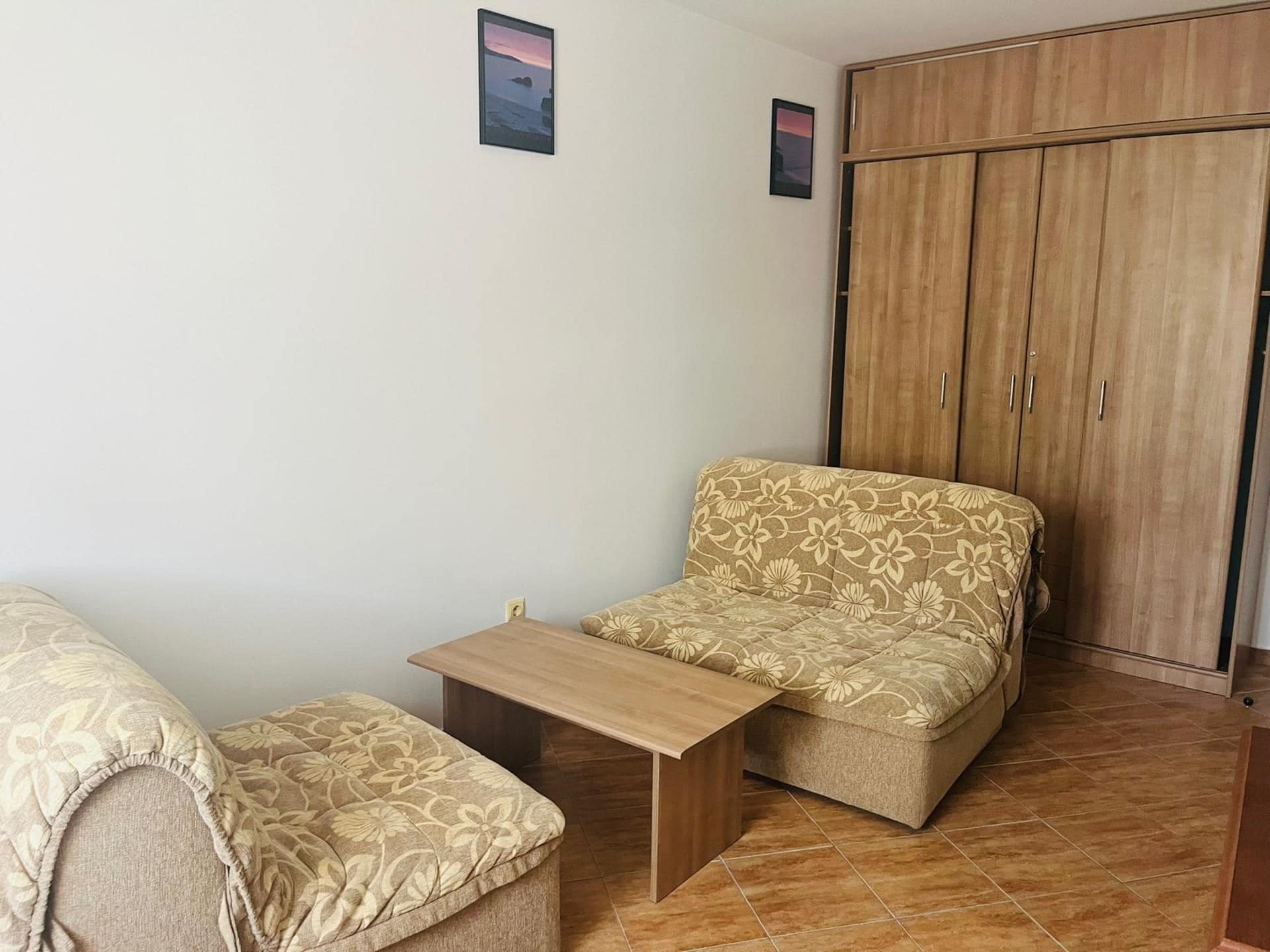 Living room in an apartment in Sutomore, Montenegro: upholstered furniture with a floral print, a coffee table, and a wooden cabinet.