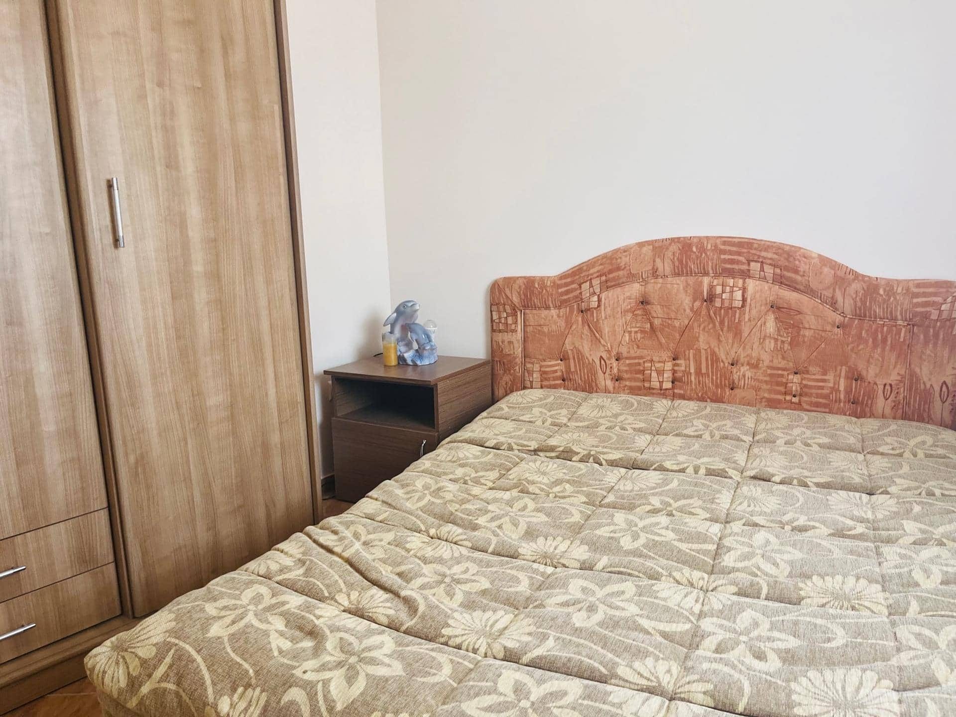 Bedroom in an apartment in Sutomore, Montenegro: a double bed with a soft headboard, a wardrobe, and a wood-look nightstand.