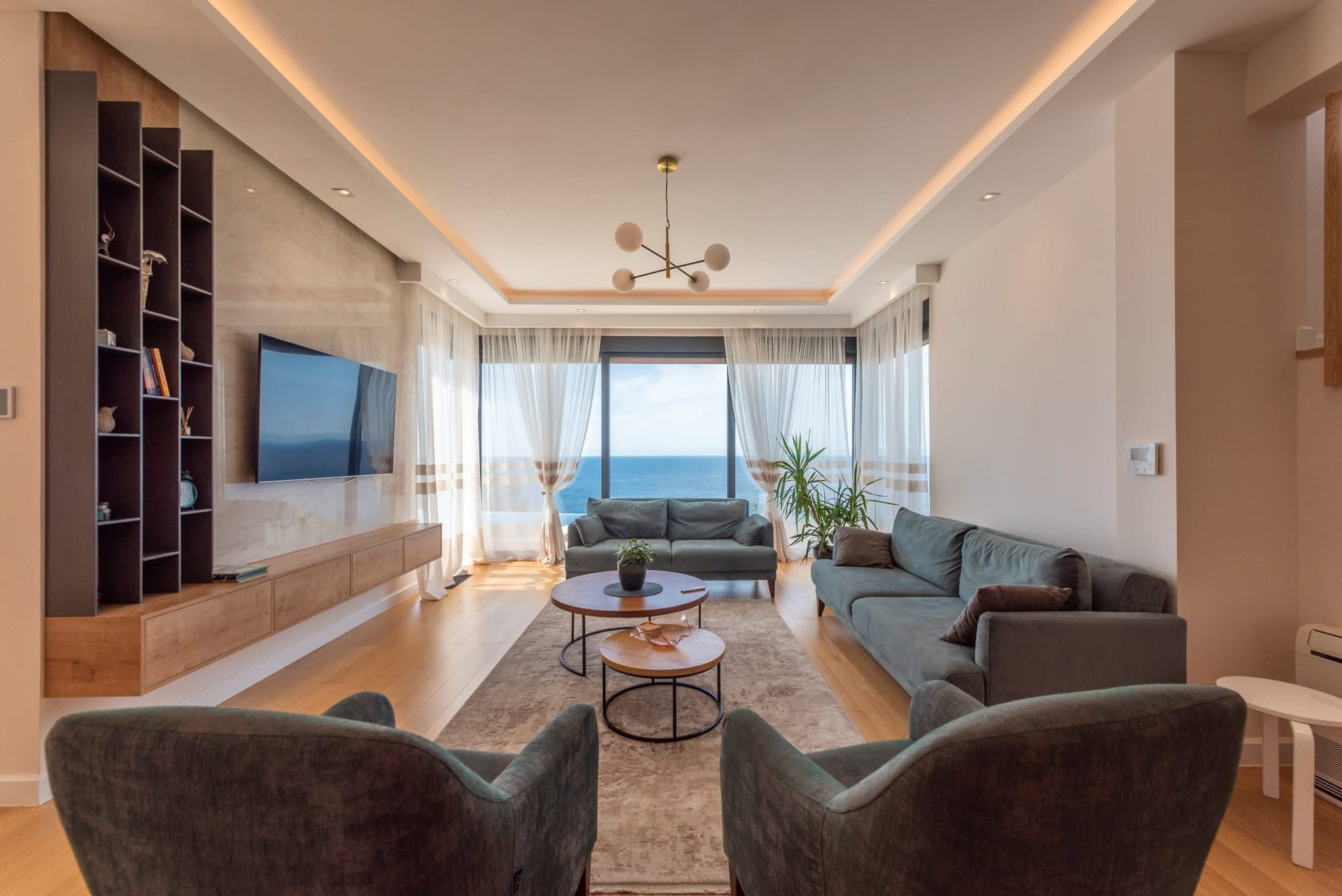 Modern living room with sea view in a house, Reževići, Montenegro: soft seating, panoramic windows, and stylish design.