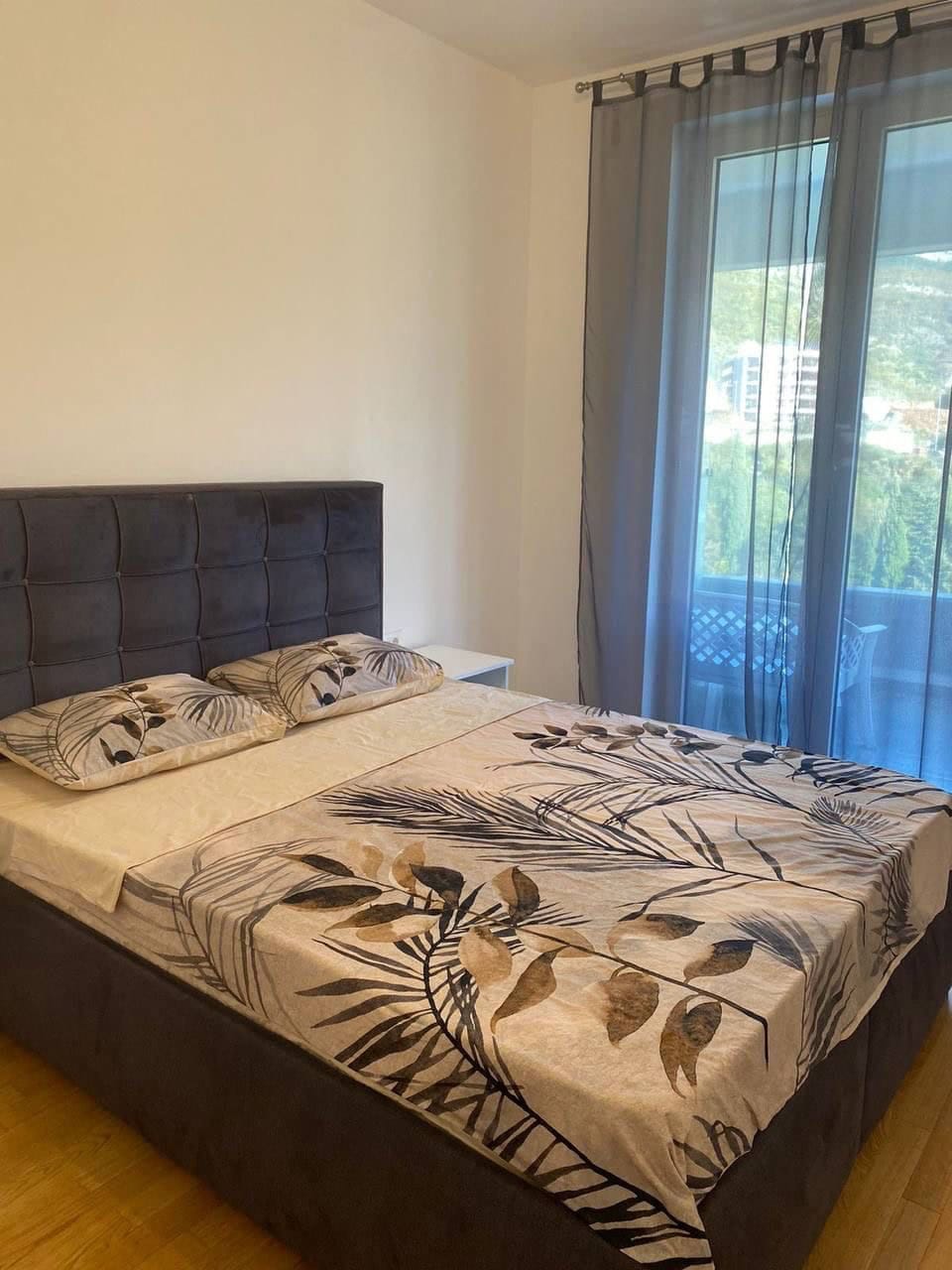 Bedroom with a double bed and access to the balcony in an apartment, Becici, Montenegro. Modern furniture, bright interior.