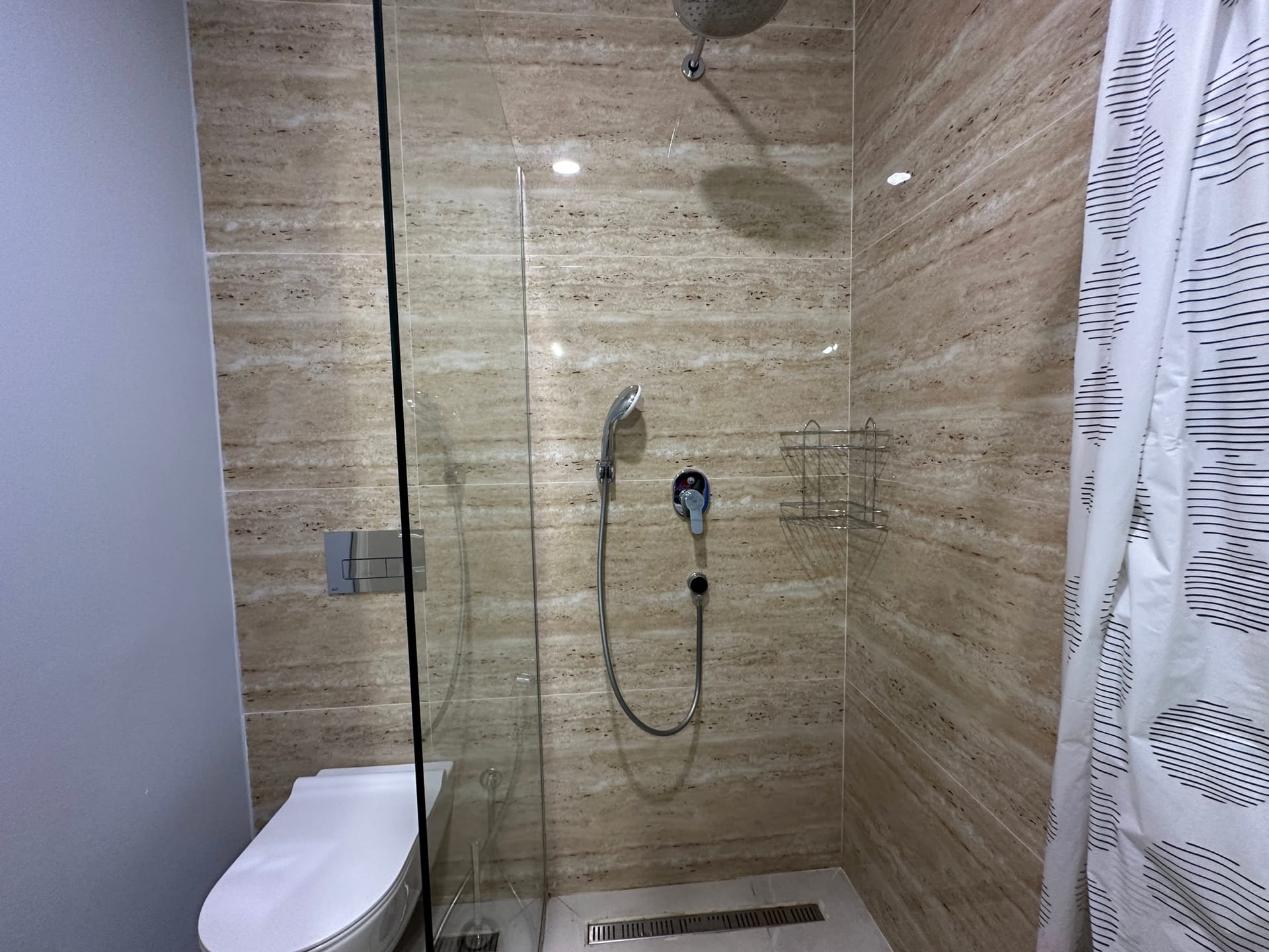 Modern bathroom with a shower cabin and travertine-style finishes in an apartment, Becici, Montenegro.