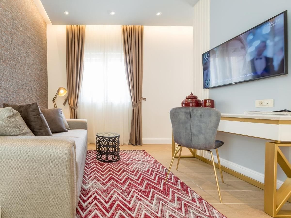 Cozy living room in a hotel in Budva, Montenegro: modern furniture, TV, a rug with a zigzag pattern, and stylish decor.