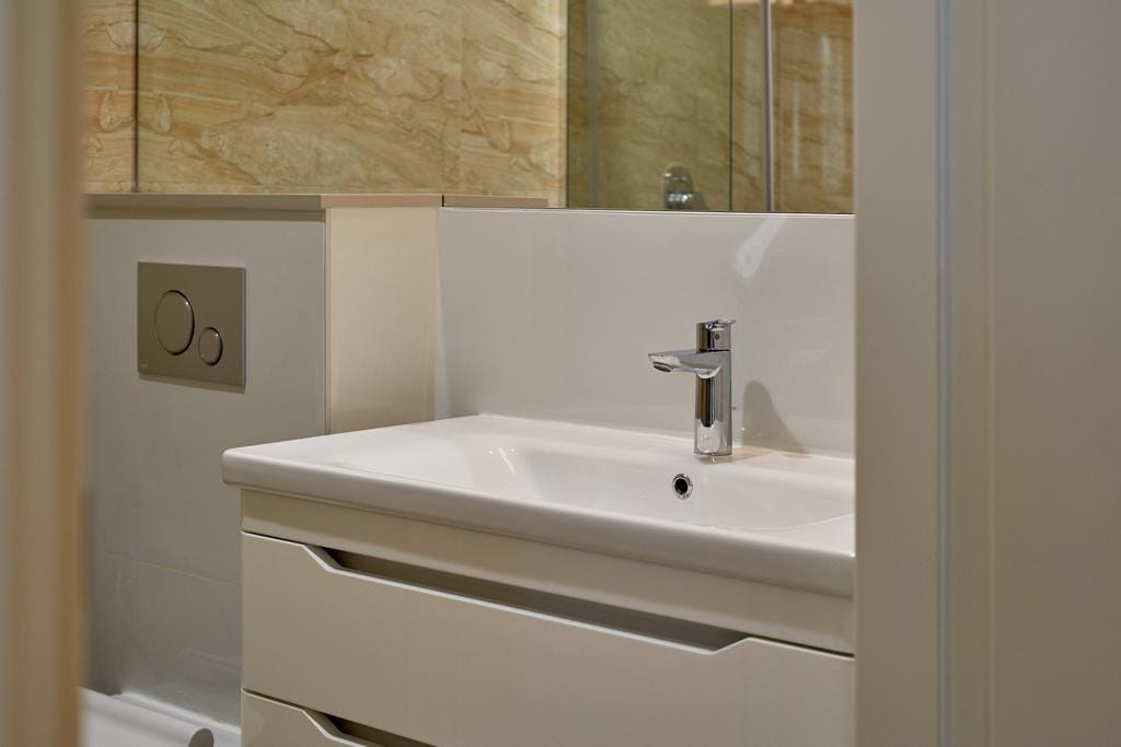 Modern bathroom in an apartment in Bečići, Montenegro: white vanity with sink and onyx-look wall tiles.