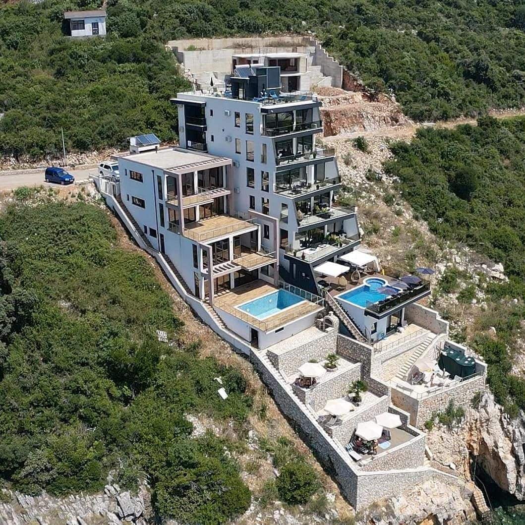 Modern villa with swimming pools and terraces on a cliff in Kruče, Montenegro: view of a luxury residential complex by the sea.