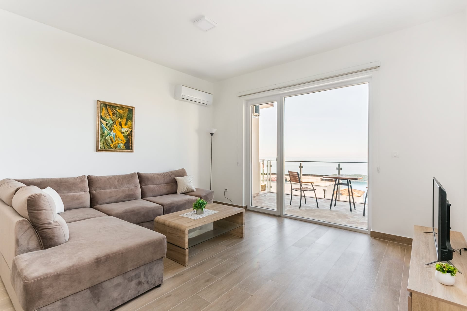 Bright living room with an L-shaped sofa and a terrace with sea view in an apartment, Seoce, Budva, Montenegro.