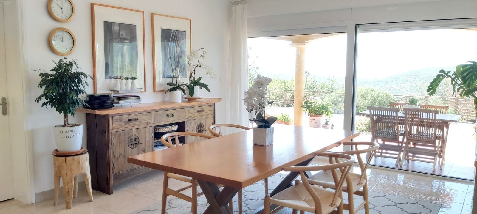 Bright living room with a wooden dining table and terrace in a house in Krimovice, Montenegro. Mountain and garden view.