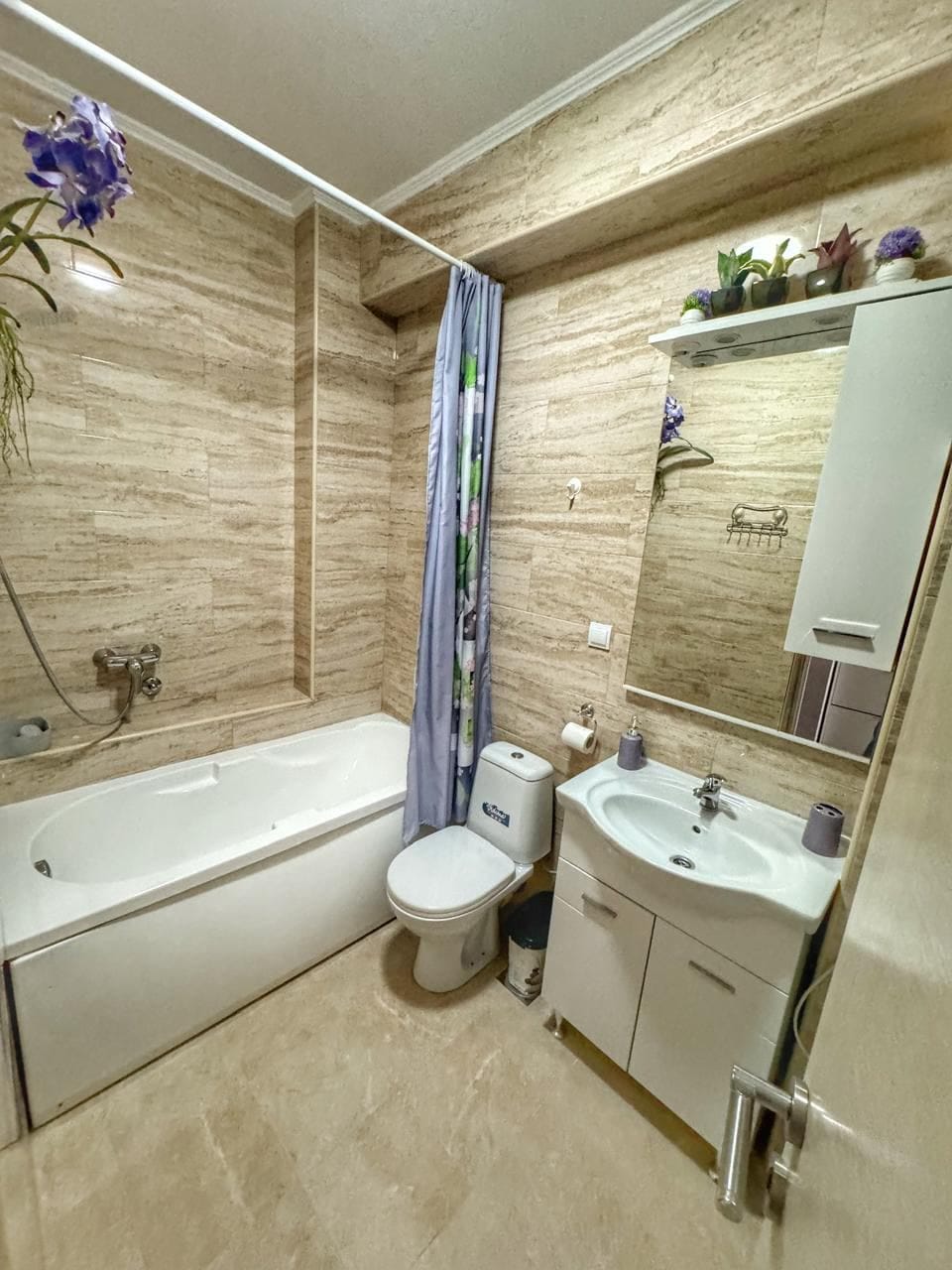 Bathroom in an apartment in Dobri Vody, Montenegro: light tiles, bathtub, vanity with sink, and mirror.