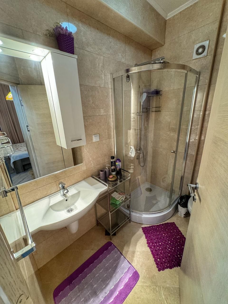 Bathroom in an apartment in Dobrye Vody, Montenegro: shower cabin, white sink, and beige wall tiles.