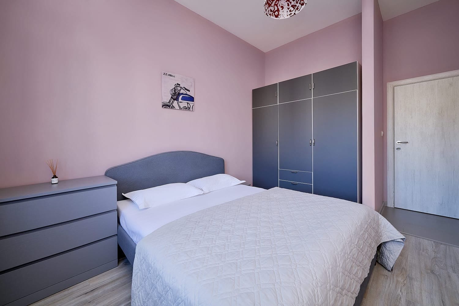 Cozy bedroom with a double bed and a grey wardrobe in an apartment in Bečići, Montenegro. Modern interior.