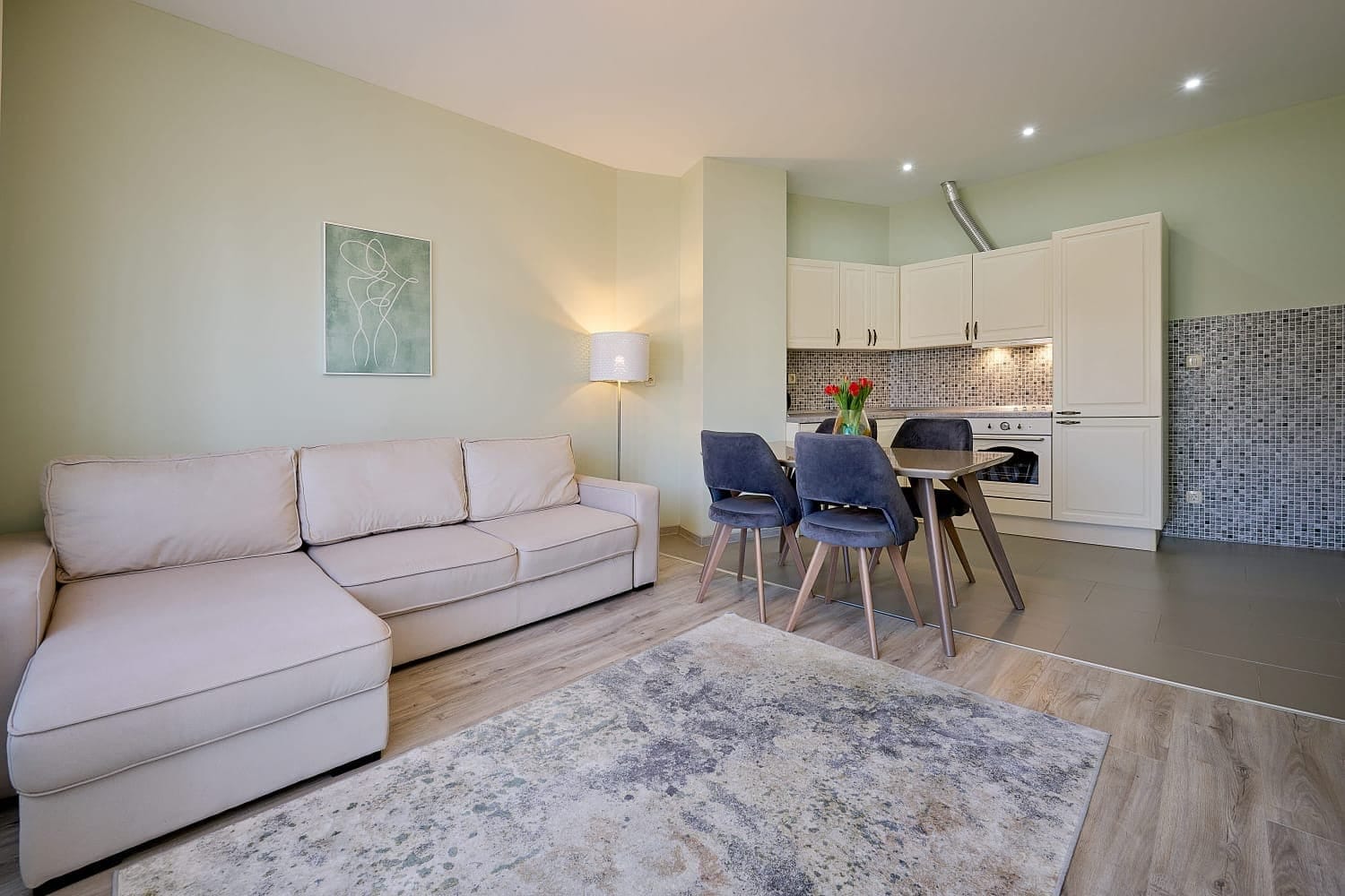 Living room with kitchen in an apartment in Bečići, Montenegro: light-colored sofa, dining area, and modern interior finishes.