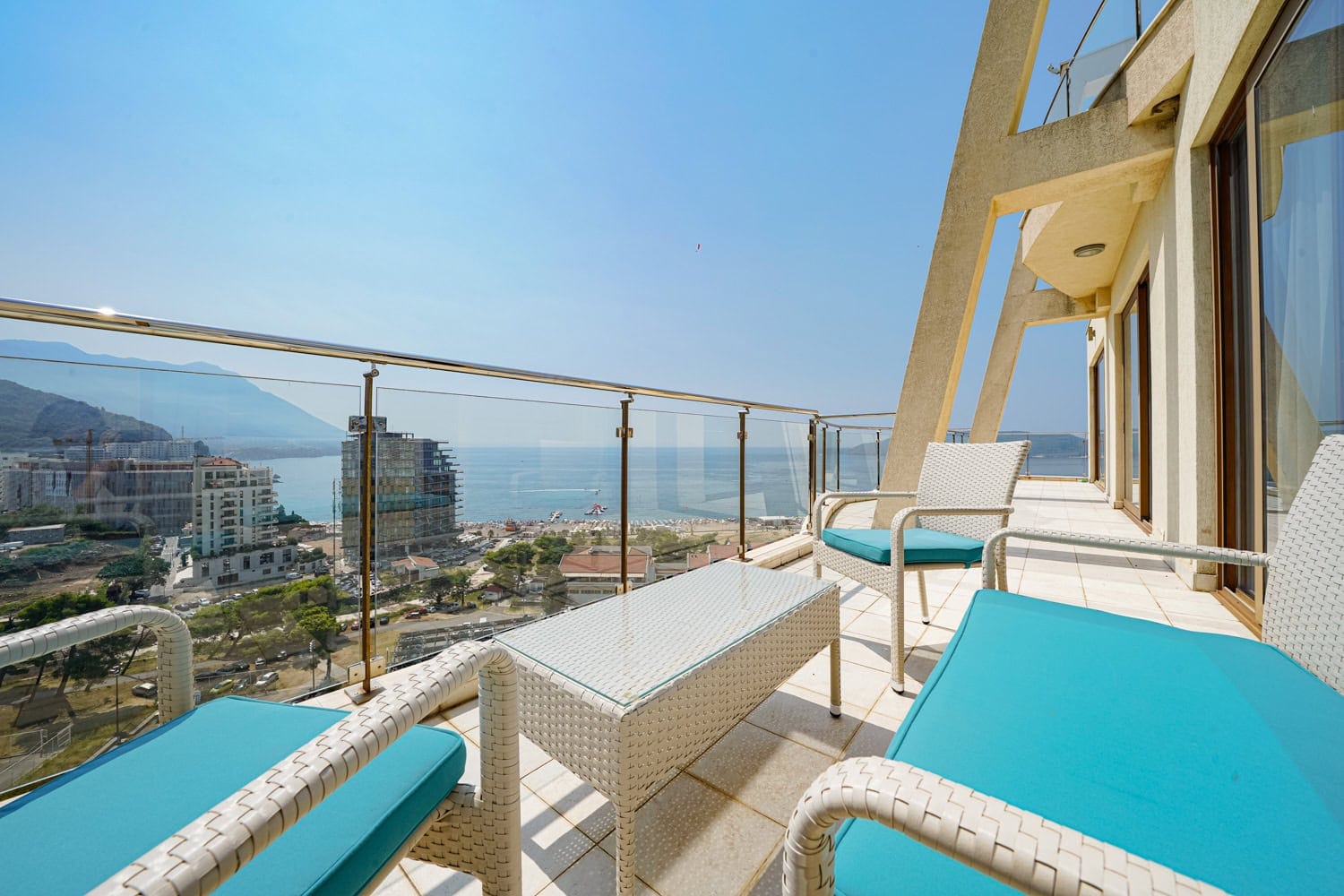 Terrace with wicker furniture and a view of the sea and beach in an apartment in Bečići, Montenegro.