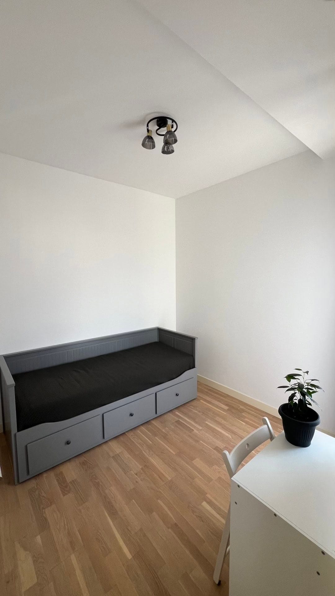Bright bedroom in an apartment, Dobrota, Montenegro: grey bed with drawers, parquet flooring, and a white desk.