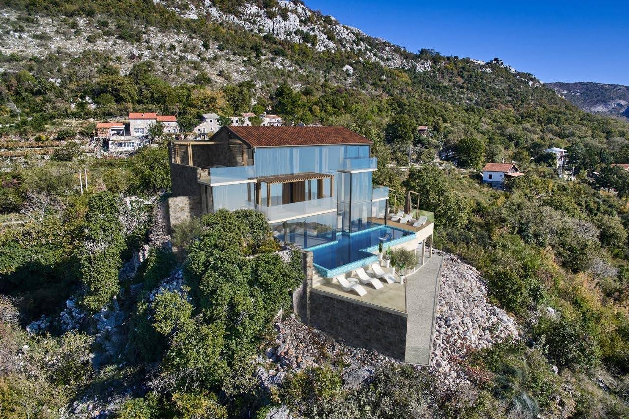 Modern villa with panoramic windows, a terrace, and a pool in the mountains of Petrovac, Montenegro. Aerial view.
