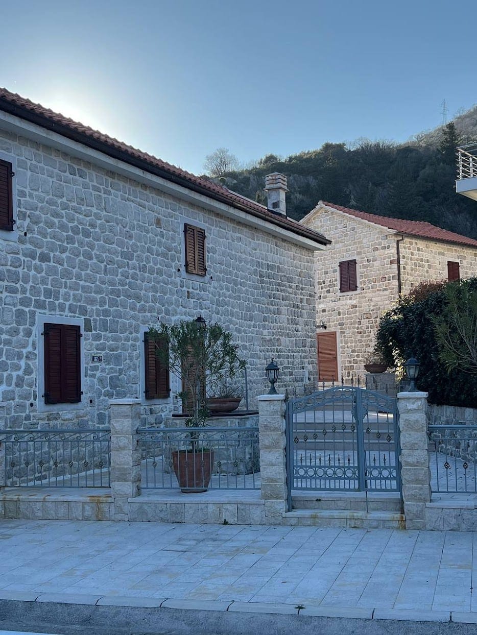Traditional stone villa in Kamenari, Montenegro: natural stone facade, wrought-iron gates, and a cozy courtyard.