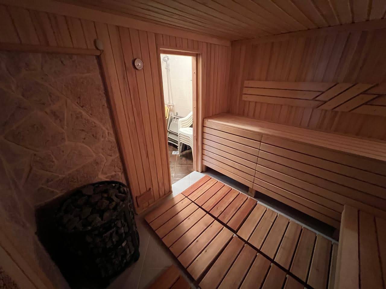 Wooden sauna with stone finishes in a villa in Kamenari, Montenegro: steam room interior with benches and a sauna stove.