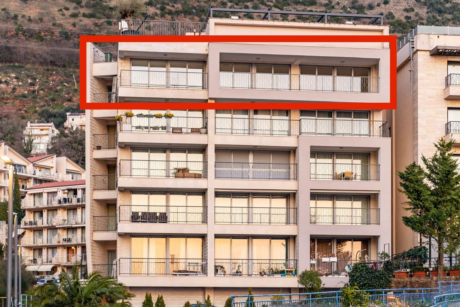 Modern apartment building in Pržno, Montenegro, with a penthouse highlighted and panoramic balconies on the facade.
