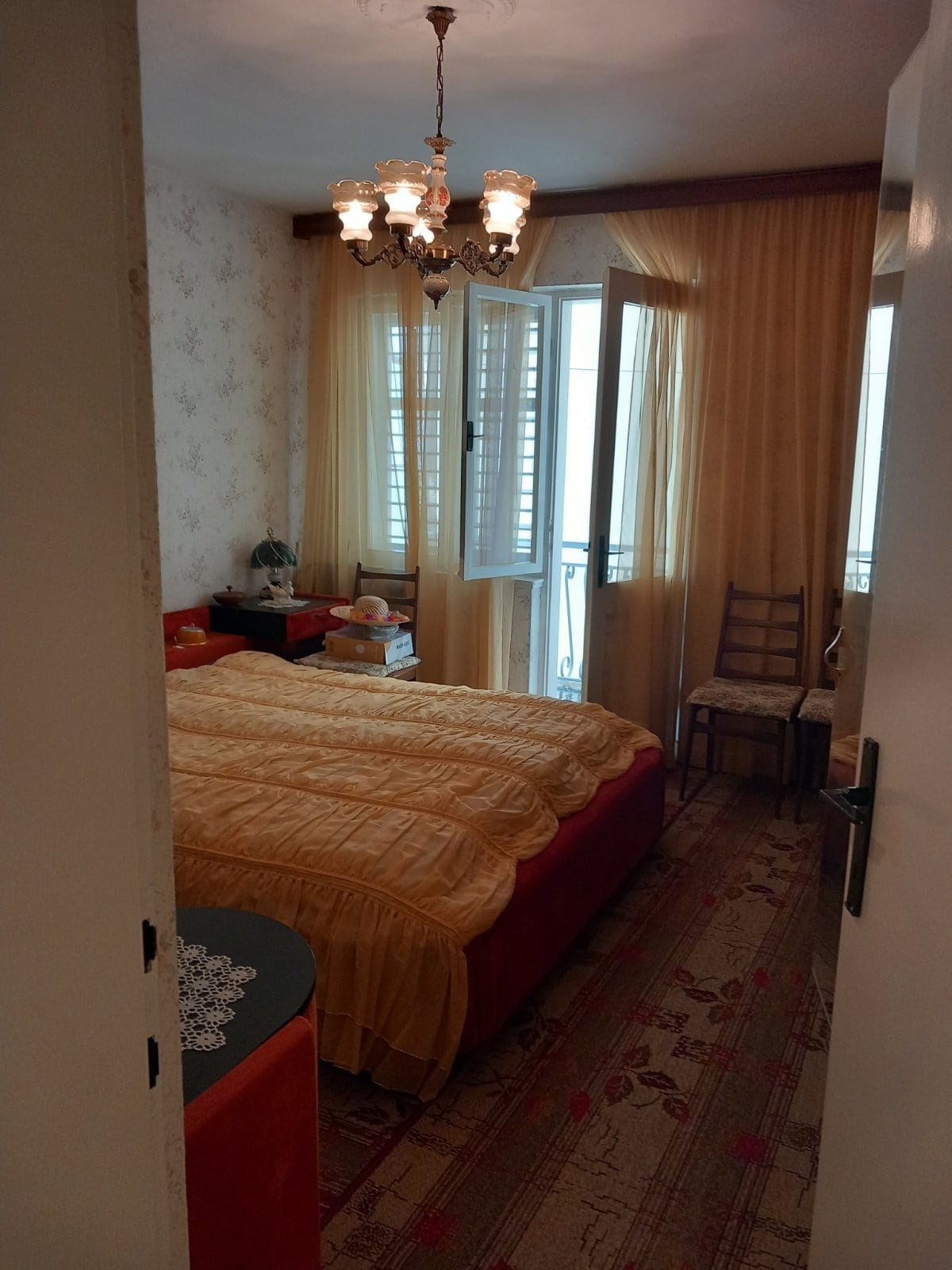 Cozy bedroom with a double bed and access to the balcony in a house, Igalo, Montenegro. Classic interior.