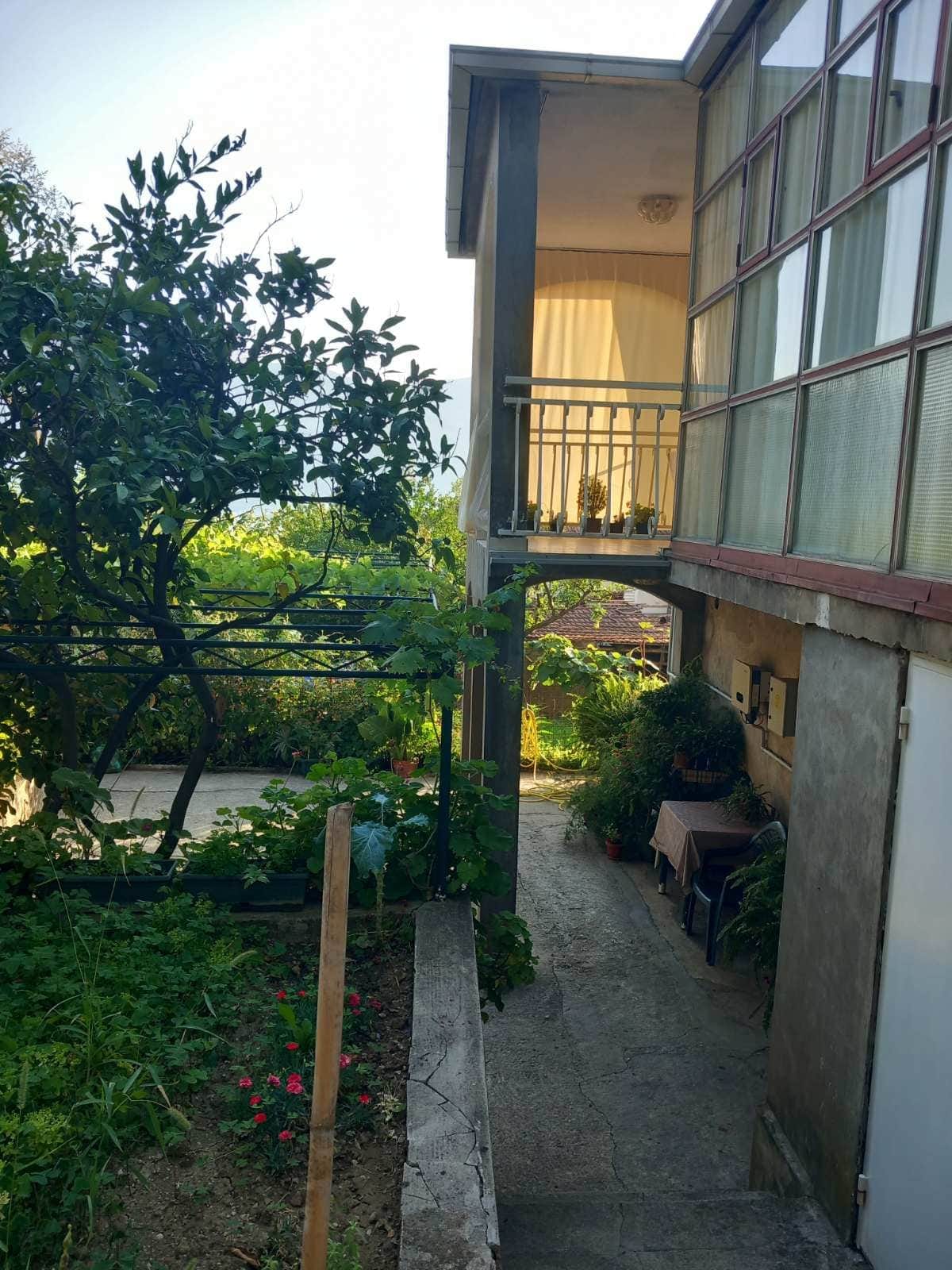 Two-story house in Igalo, Montenegro: terrace, panoramic windows, and a green garden with a vineyard in the yard.