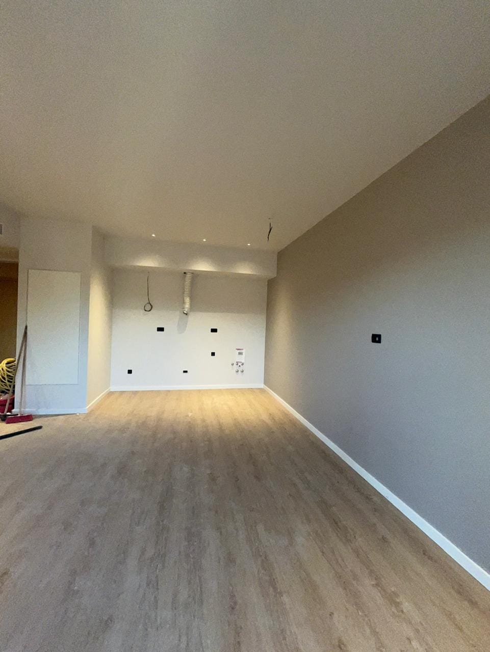 Living room in a new apartment in Tivat, Montenegro: light finishes, laminate flooring, recessed lighting, and utility connections for appliances.