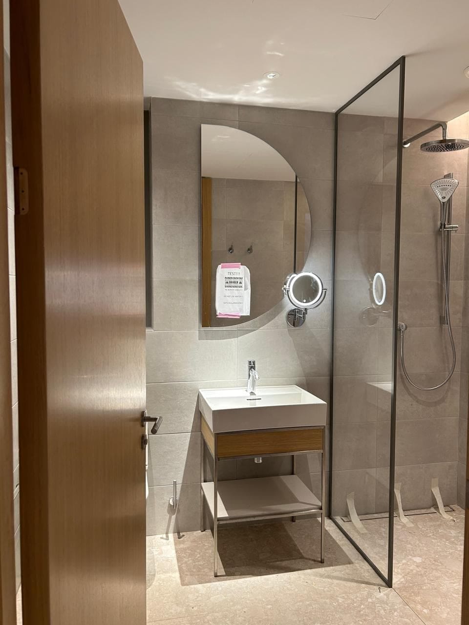 Modern bathroom in an apartment in Tivat, Montenegro: shower cabin, stylish sink, and backlit mirror.
