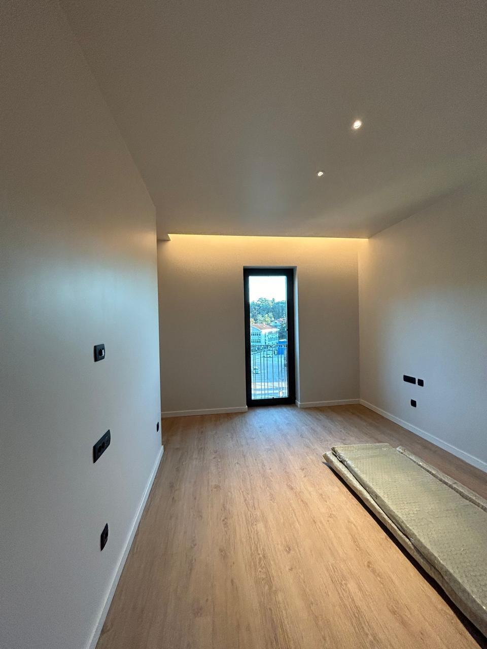 Modern bedroom in an apartment in Tivat, Montenegro: light finishes, laminate flooring, hidden lighting, and a view from the window.