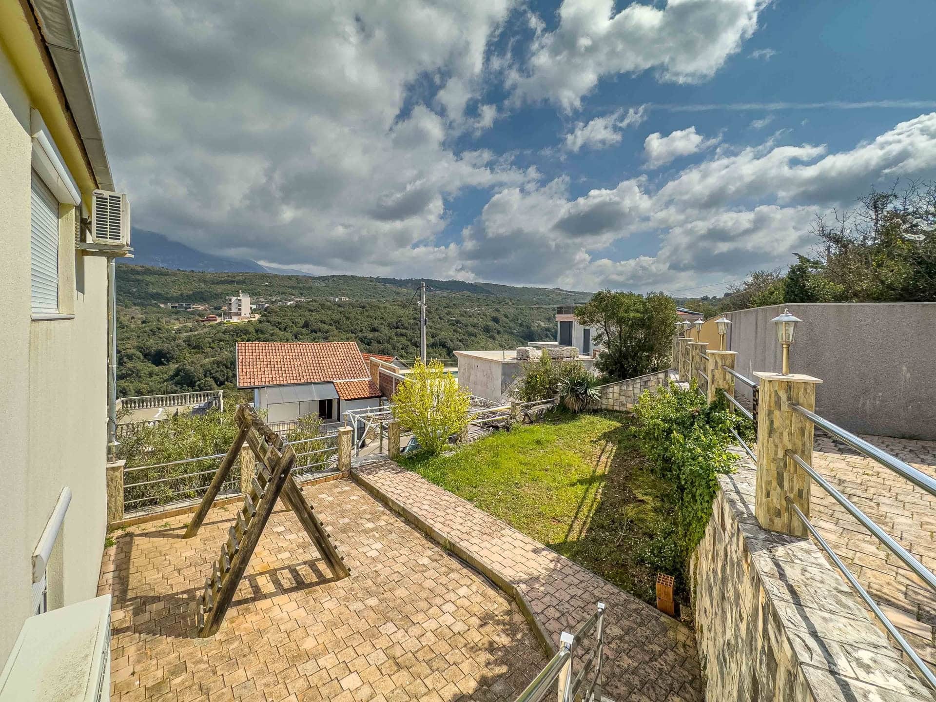Terrace with a playground and mountain view by the house in Uteha, Montenegro: paved area, garden, and panoramic scenery.