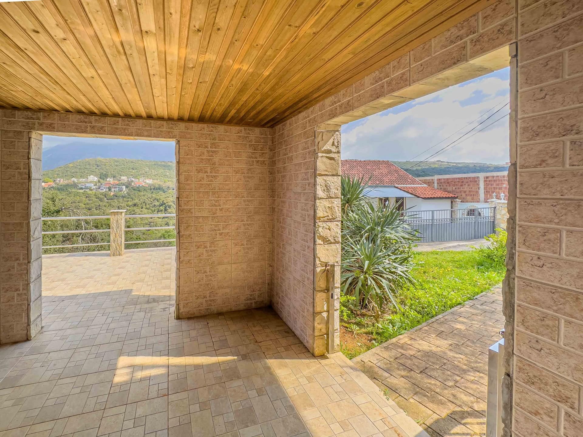 Covered terrace with stone finishes and a wooden ceiling in the house, Utjeha, Montenegro, mountain and garden view.