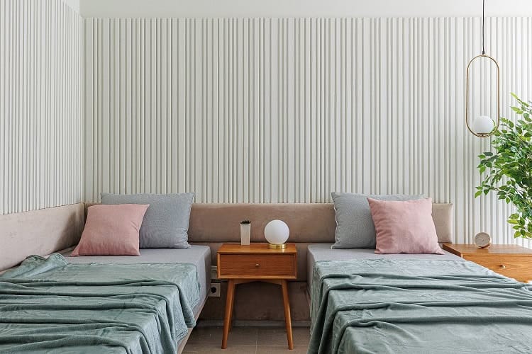 Bedroom in an apartment in Bečići, Montenegro: two beds, wooden nightstands, slatted wall paneling, and stylish interior decor.