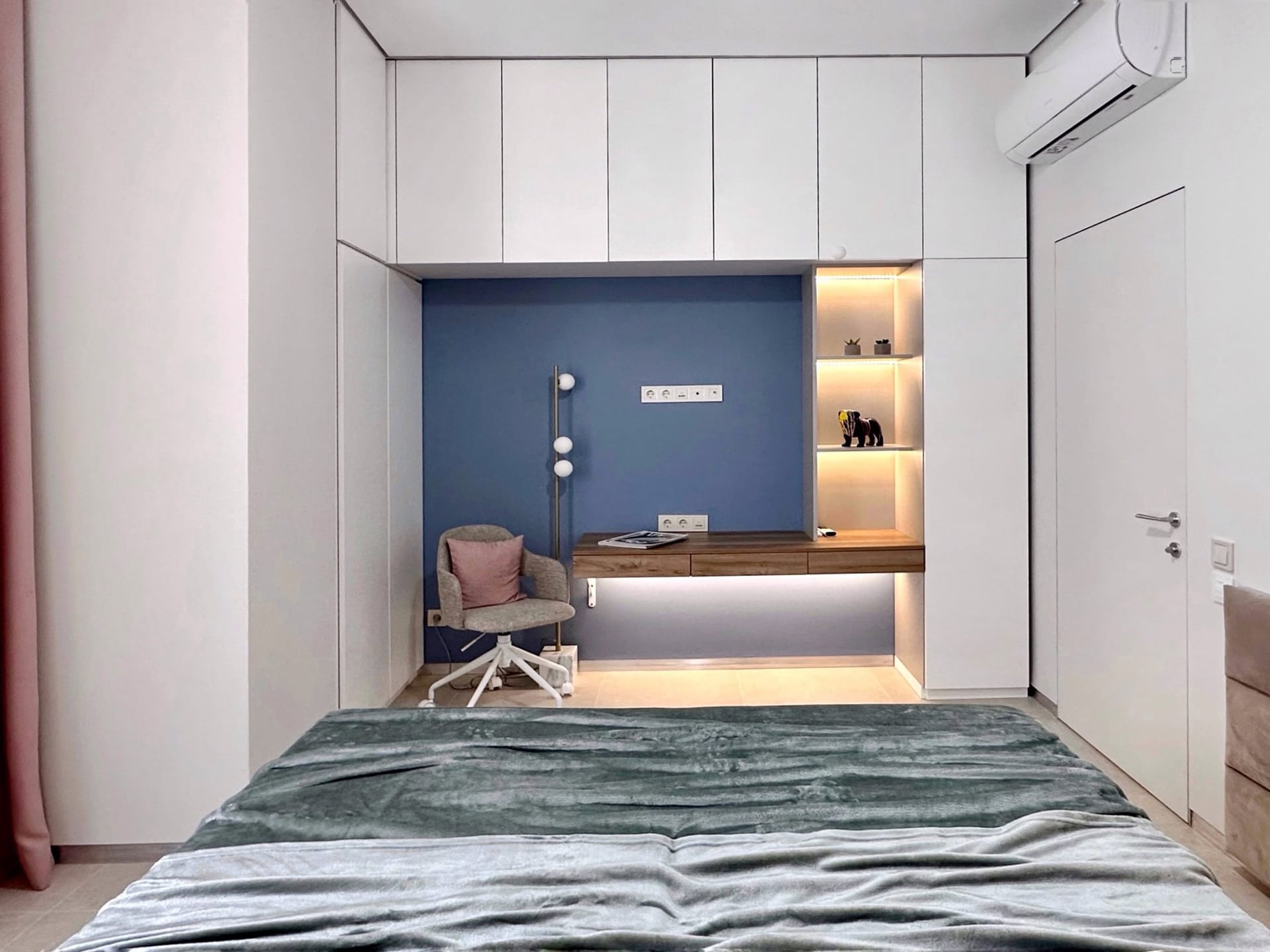 Modern bedroom in an apartment in Bečići, Montenegro: built-in wardrobe, workspace with lighting, and a bed.