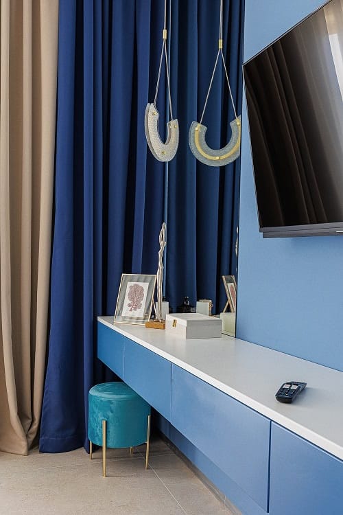 Modern living room in a Becici apartment, Montenegro: blue furniture, designer lighting, and TV area.
