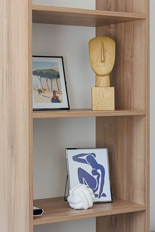 Wooden shelving unit with decor and paintings in a living room interior in Bečići, Montenegro. Stylish living room design.