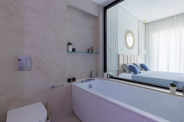 Modern bathroom with a panoramic window overlooking the bedroom in an apartment, Bečići, Montenegro. Marble-effect tile finish.