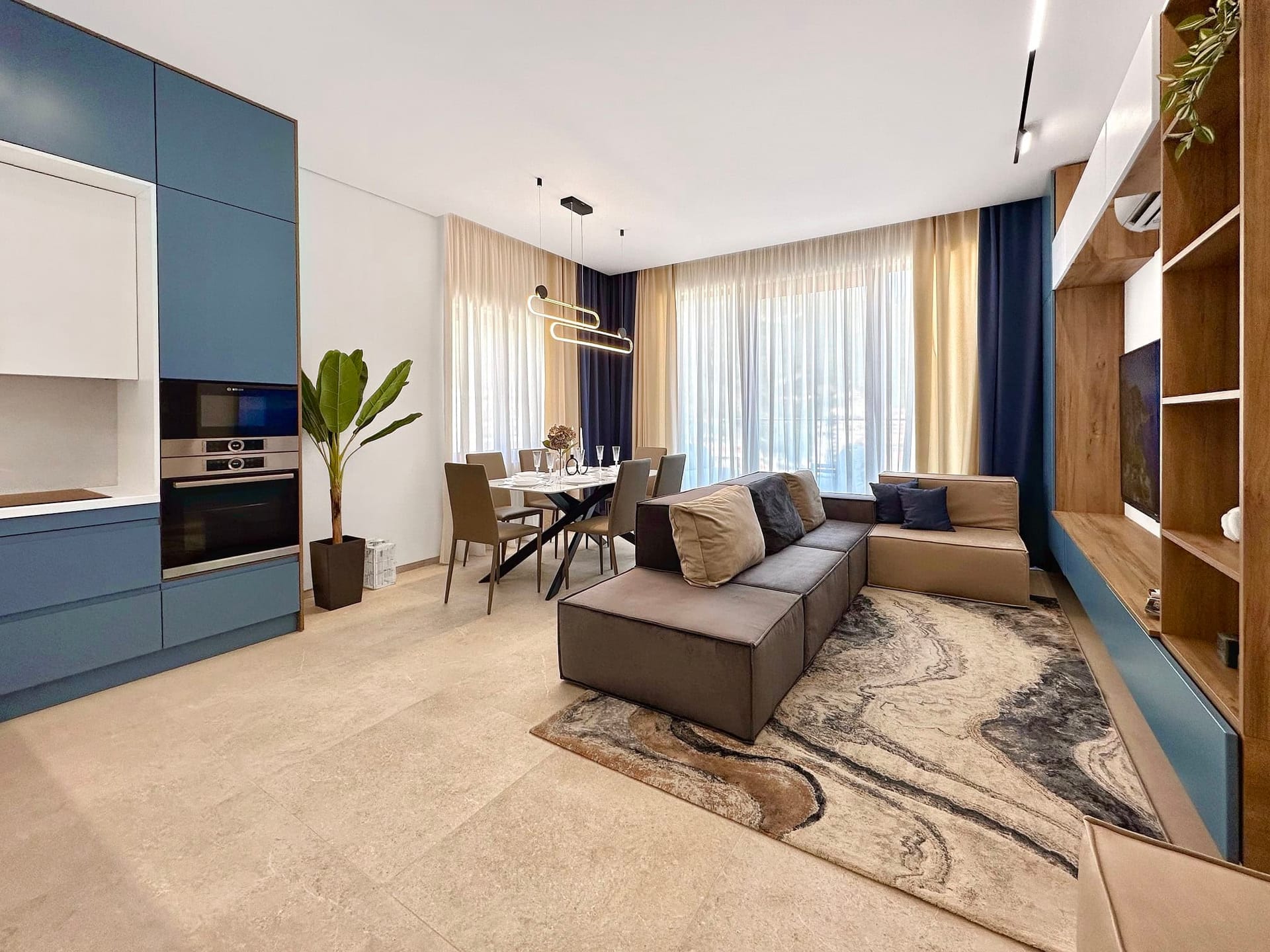 Modern living room with kitchen in an apartment, Becici, Montenegro: stylish furniture, dining area, and panoramic windows.