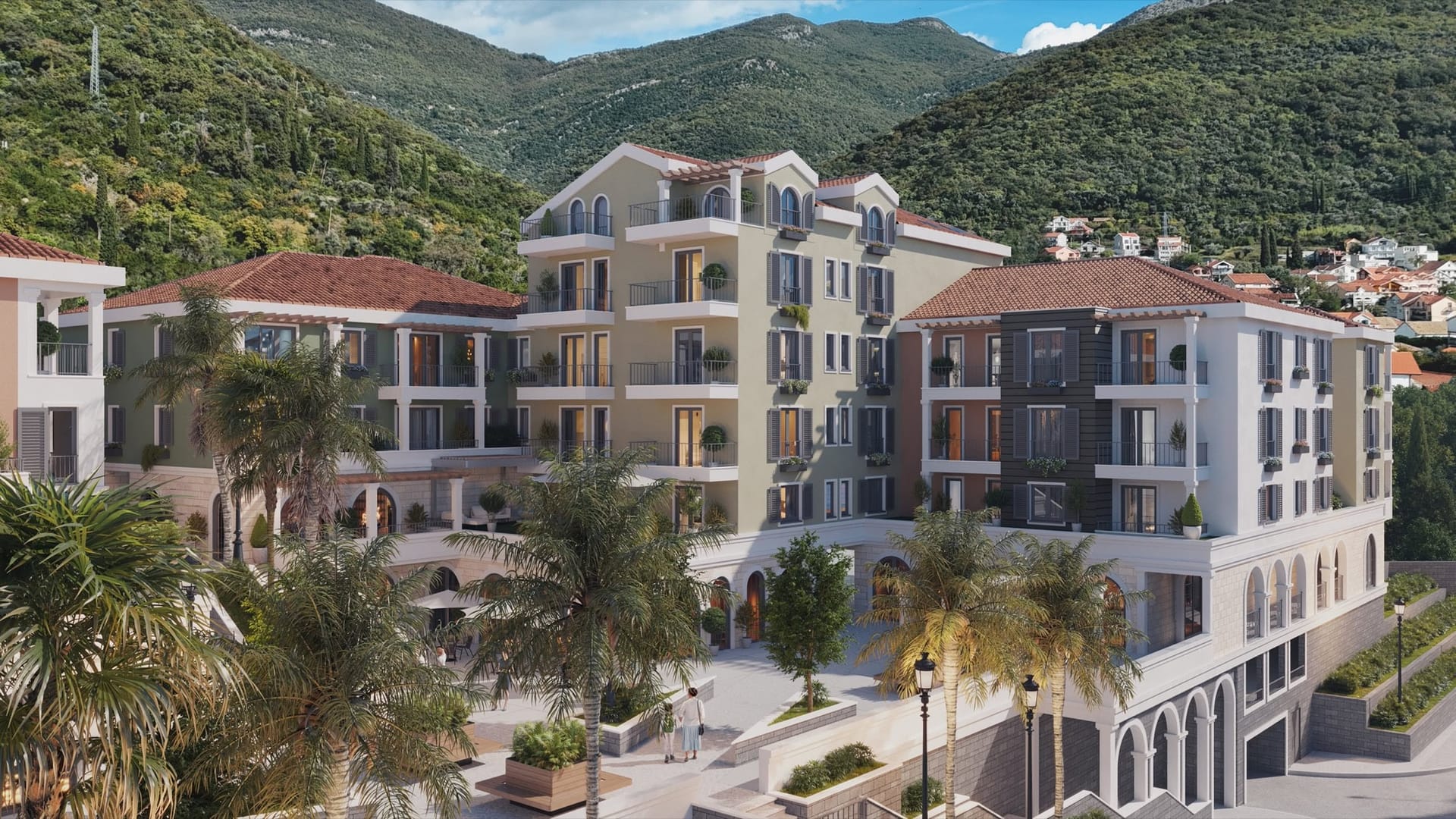 Modern residential complex with terraces and palm trees in Tivat, Montenegro: view of the building facade against the backdrop of mountains.