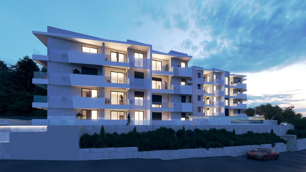 Modern residential complex in Petrovac, Montenegro: building facade with terraces, panoramic windows, and evening lighting